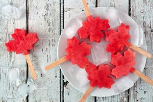 Canadian maple leaf watermelon pops on a plate against rustic white wood