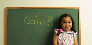 Girl standing by chalkboard with GATO on it
