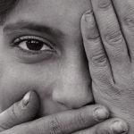 Black & white photo of Syrian girl showing one eye, closing mouth.