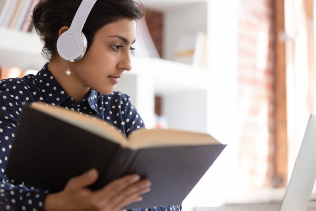 Female translator with headphones using professional literature