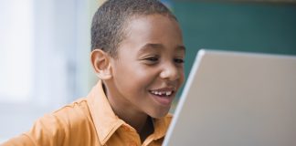 Happy African-American boy working on laptop