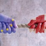 Tug of war between hands painted with UK and European flags
