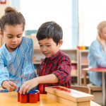 kids folding educational game with teacher at background in montessori class
