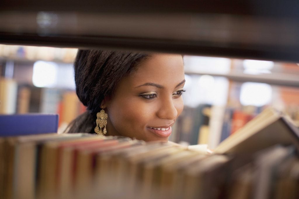 Smiling girl examining book in library